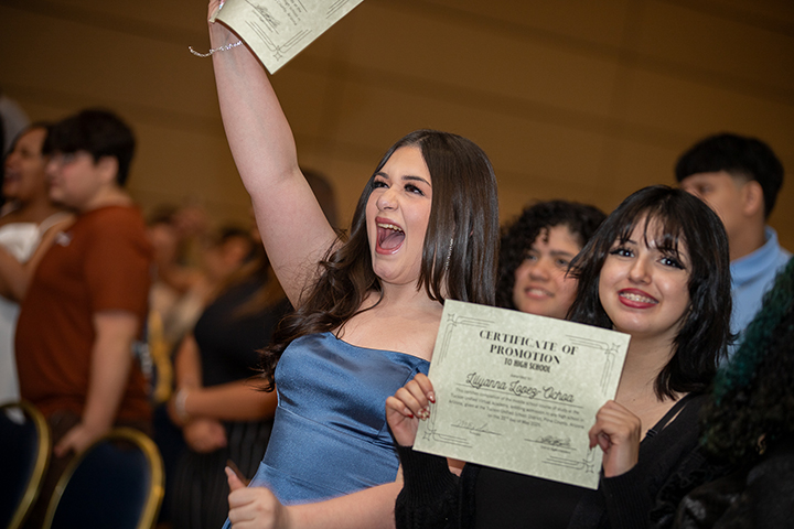Two girls proudly hold up their certificate of promotion