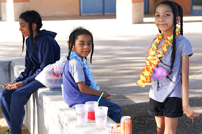 Two students wearing leis smile for a photo outside
