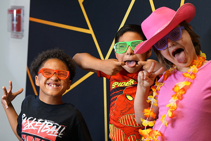 Three students make silly photos in their colorful sunglasses