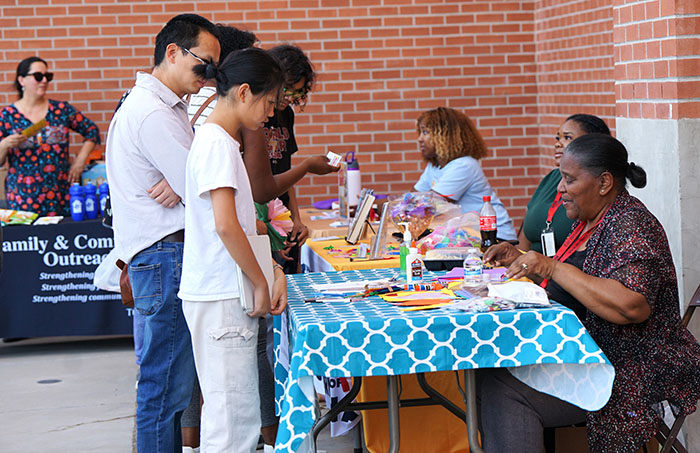 Women sitting behind a table talk to families