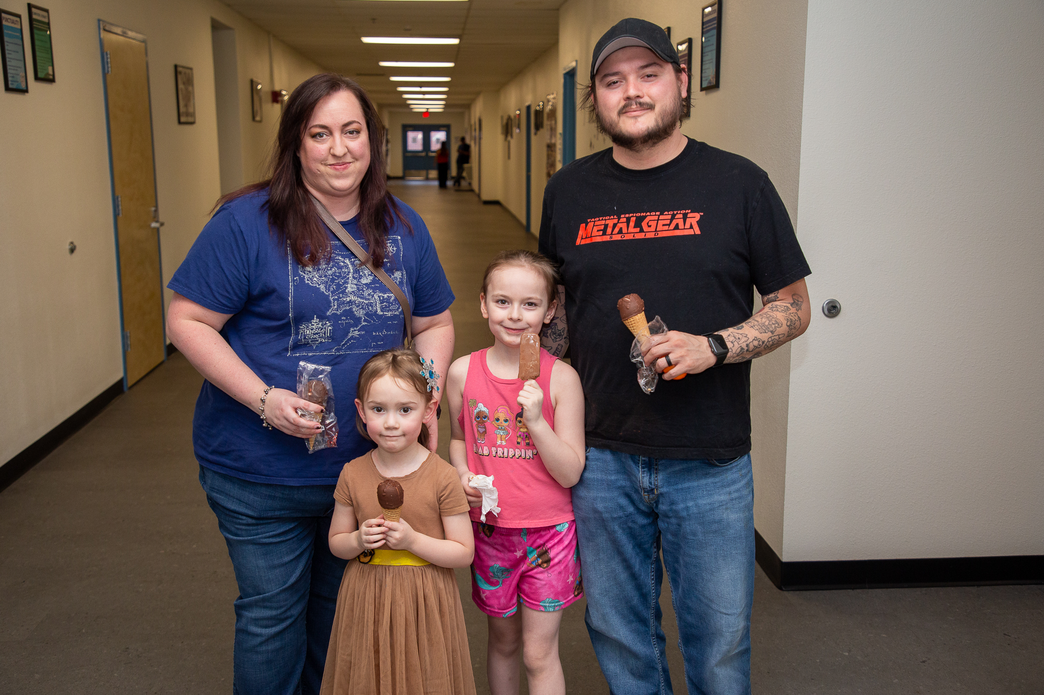 Two girls and their mom and dad smile and hold up their ice cream treats