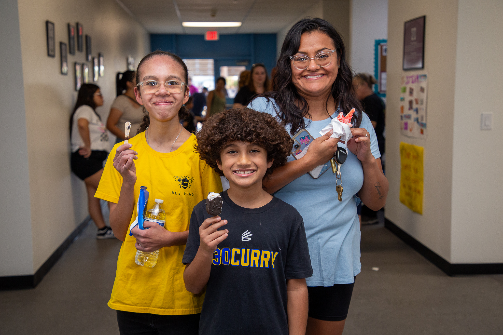 A sister and brother and their mom smile with their ice cream treats