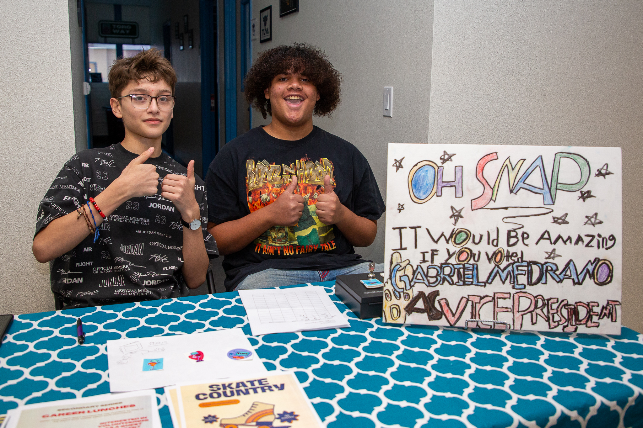 Two boys give thumbs up at their table at the ice cream social