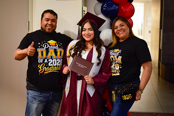 A graduate poses for a photo after the ceremony with her dad and mom